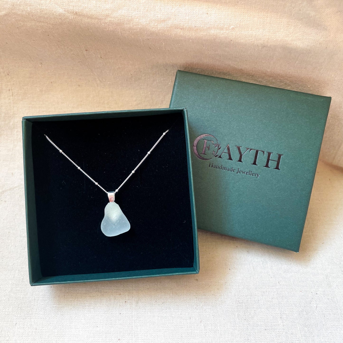 light blue sea glass necklace on a silver satellite chain in a dark green gift box with black foam insert