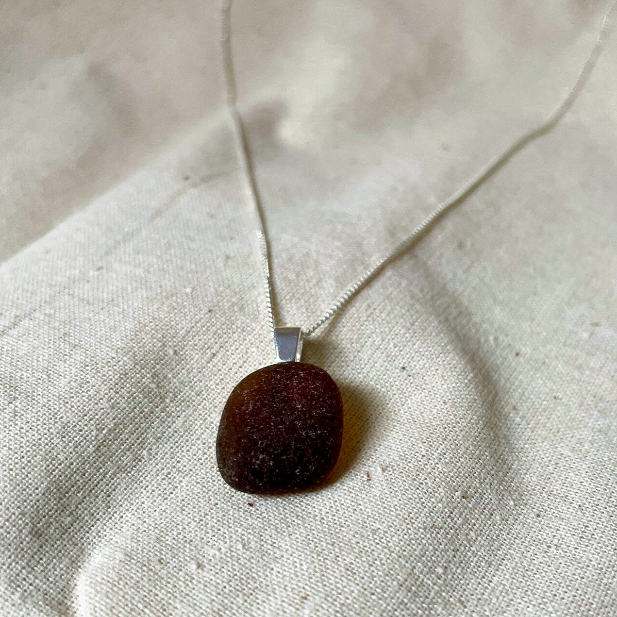 Brown sea glass necklace on beige background