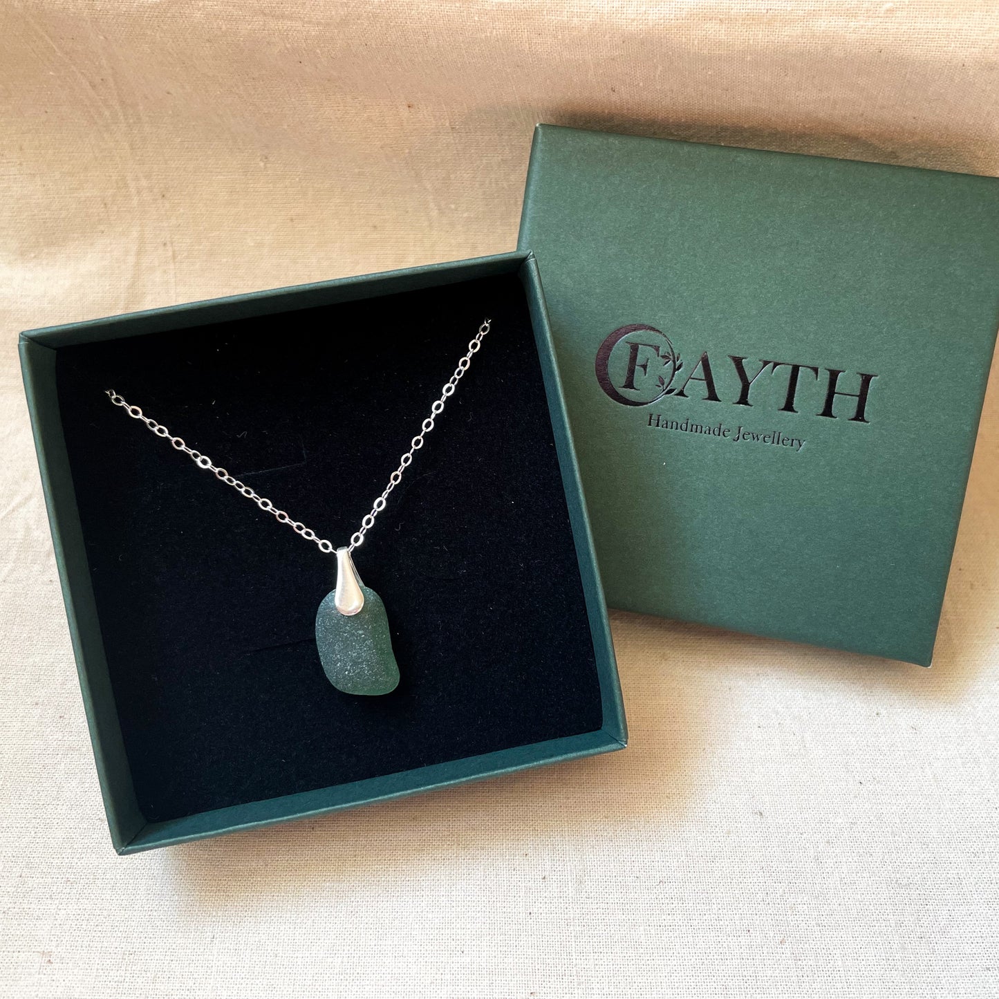 Green sea glass necklace on silver chain in a dark green gift box with black foam insert