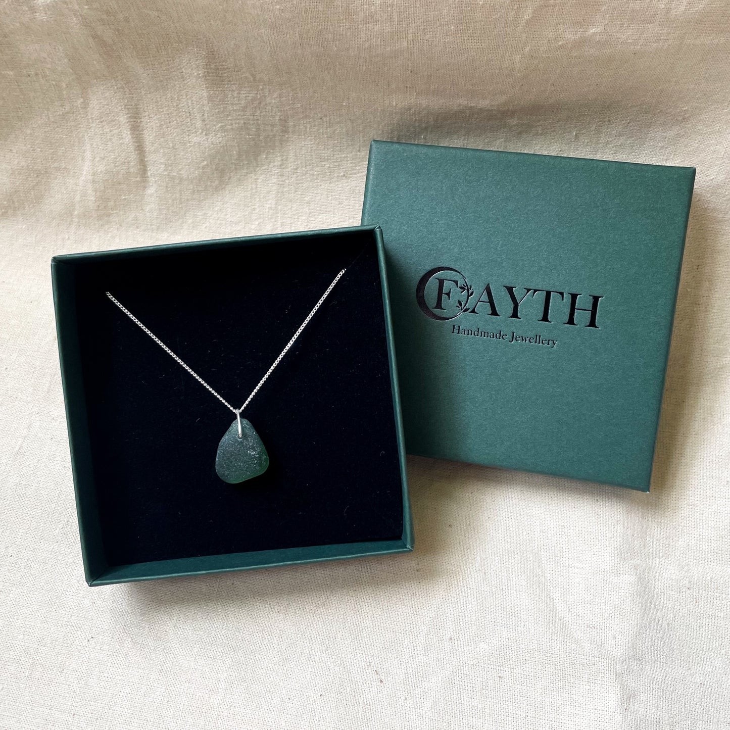 Green sea glass necklace on a fine silver chain in a dark green gift box with black foam insert