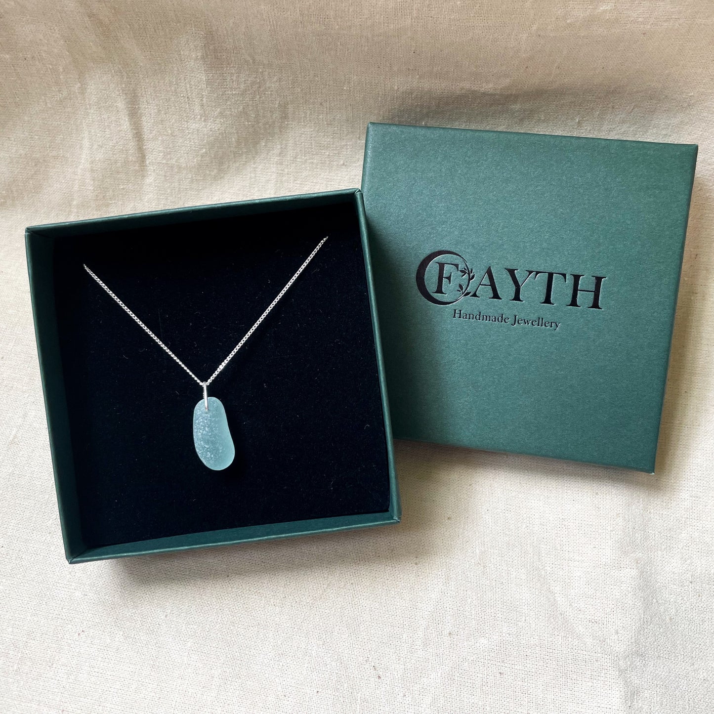 Blue sea glass necklace on a fine silver chain in a dark green gift box with black foam insert