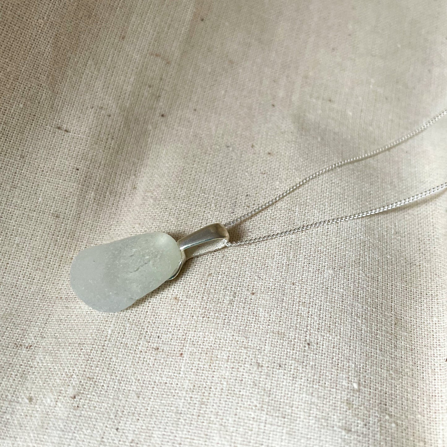 White sea glass necklace on beige background