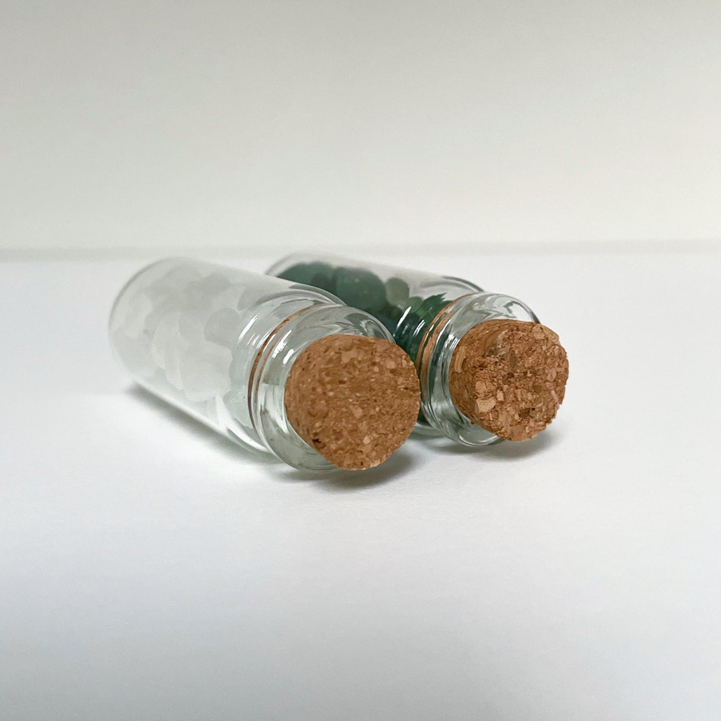 mini glass bottles of sea glass with cork lids laid down showing the cork lids close up