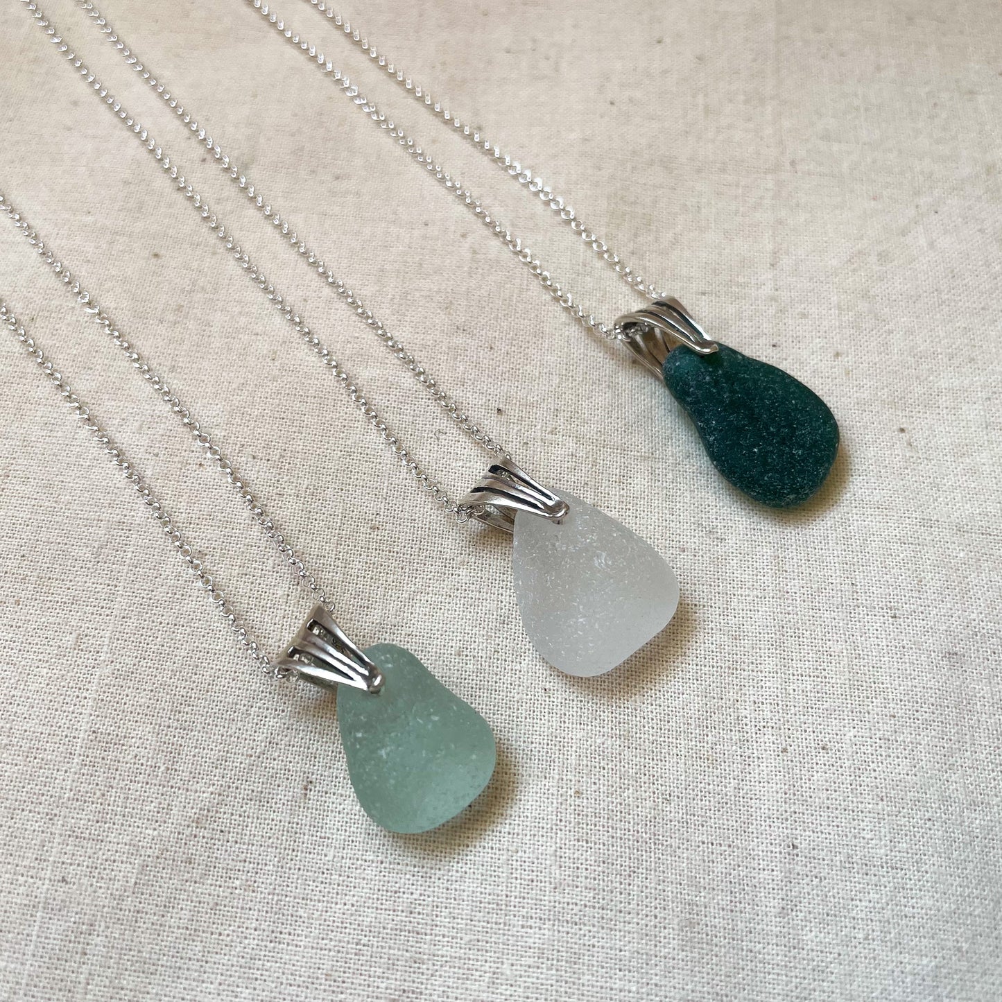 Sea glass necklaces, in light blue (left), white (middle) and green (right) on silver chains