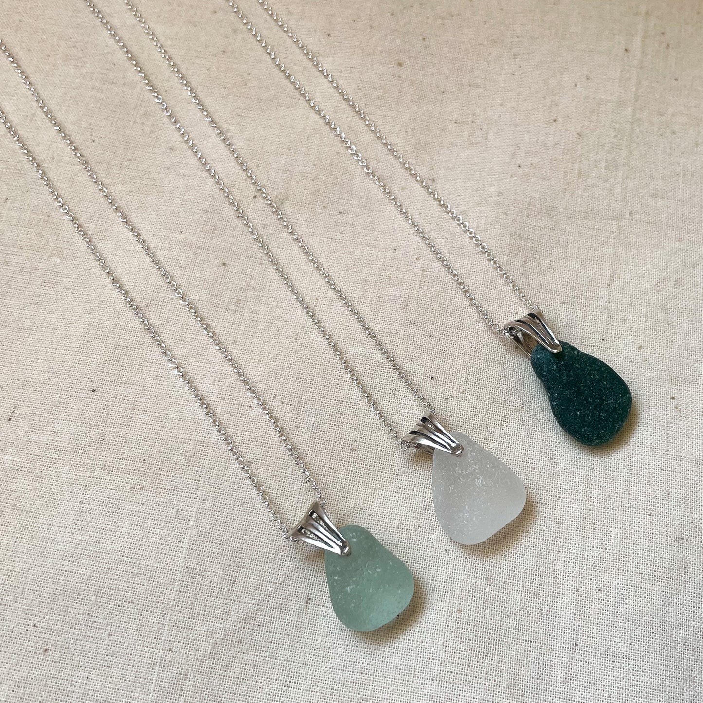 Sea glass necklaces, in light blue (left), white (middle) and green (right) on silver chains