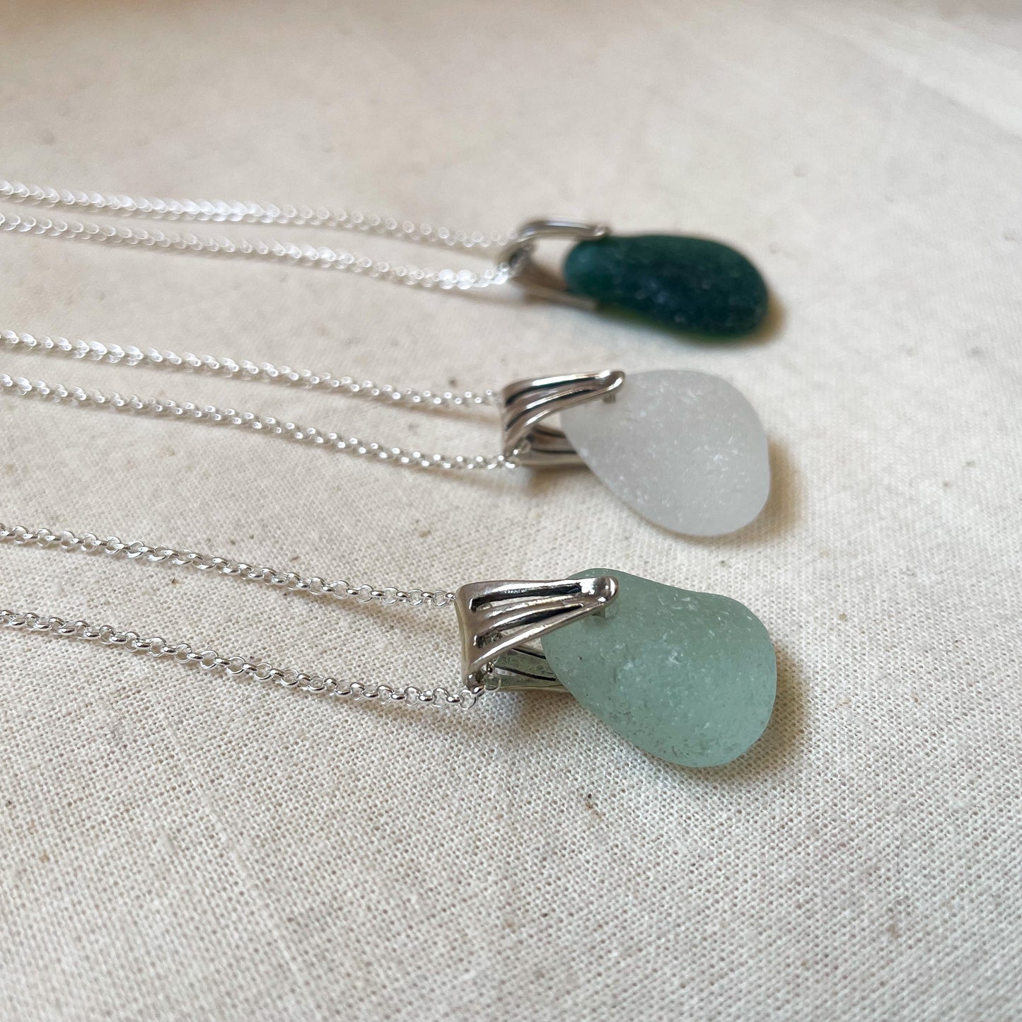 Sea glass necklaces, in light blue (left), white (middle) and green (right) on silver chains