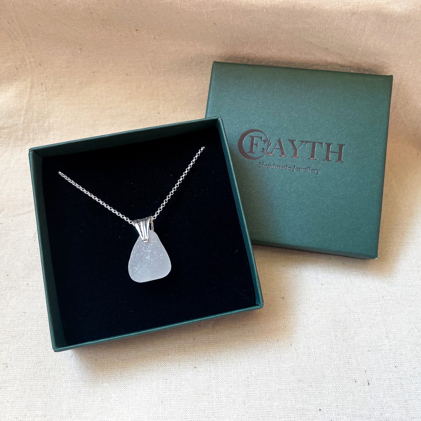 White sea glass necklace on a silver belcher chain in a dark green gift box with black foam insert