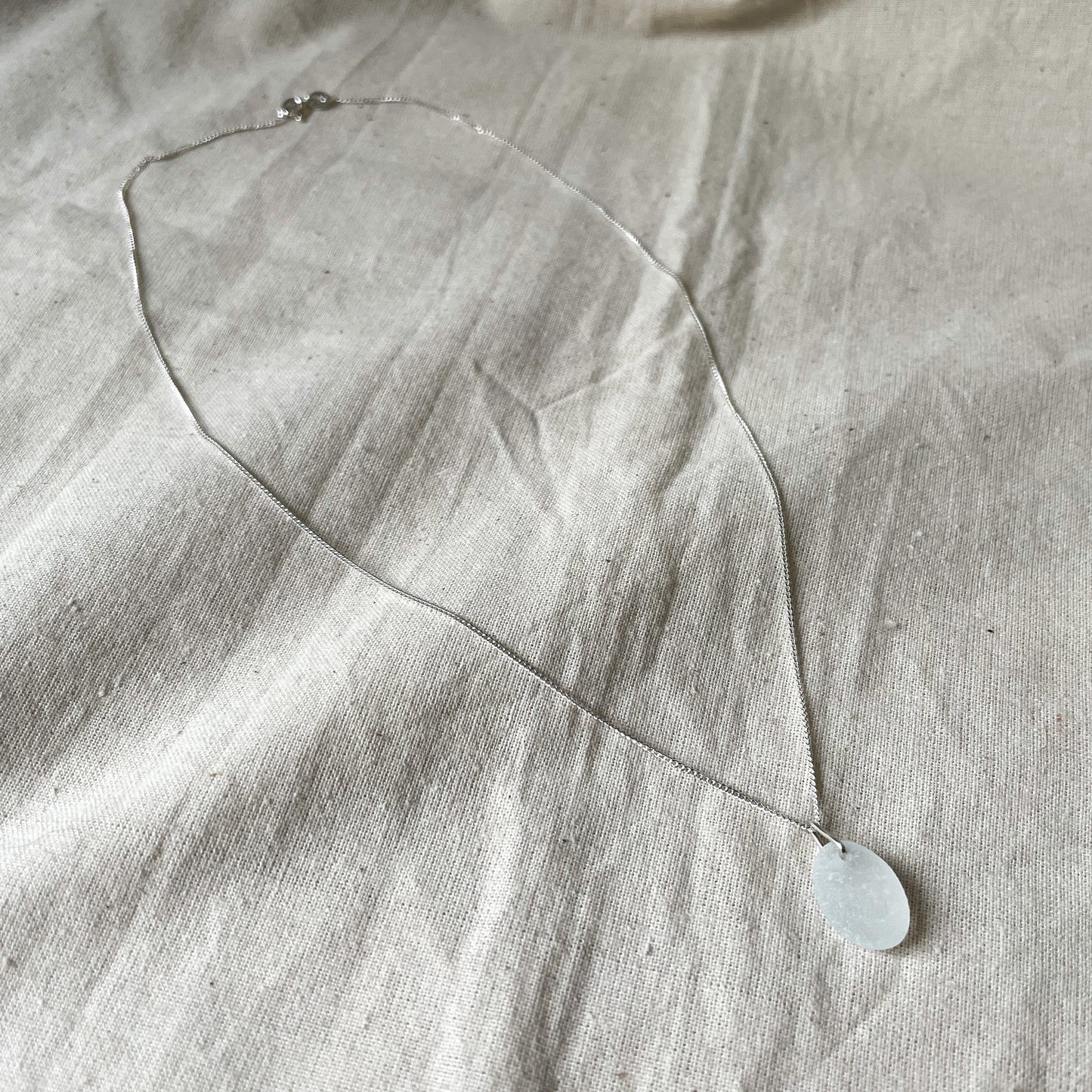 White sea glass necklace on beige background