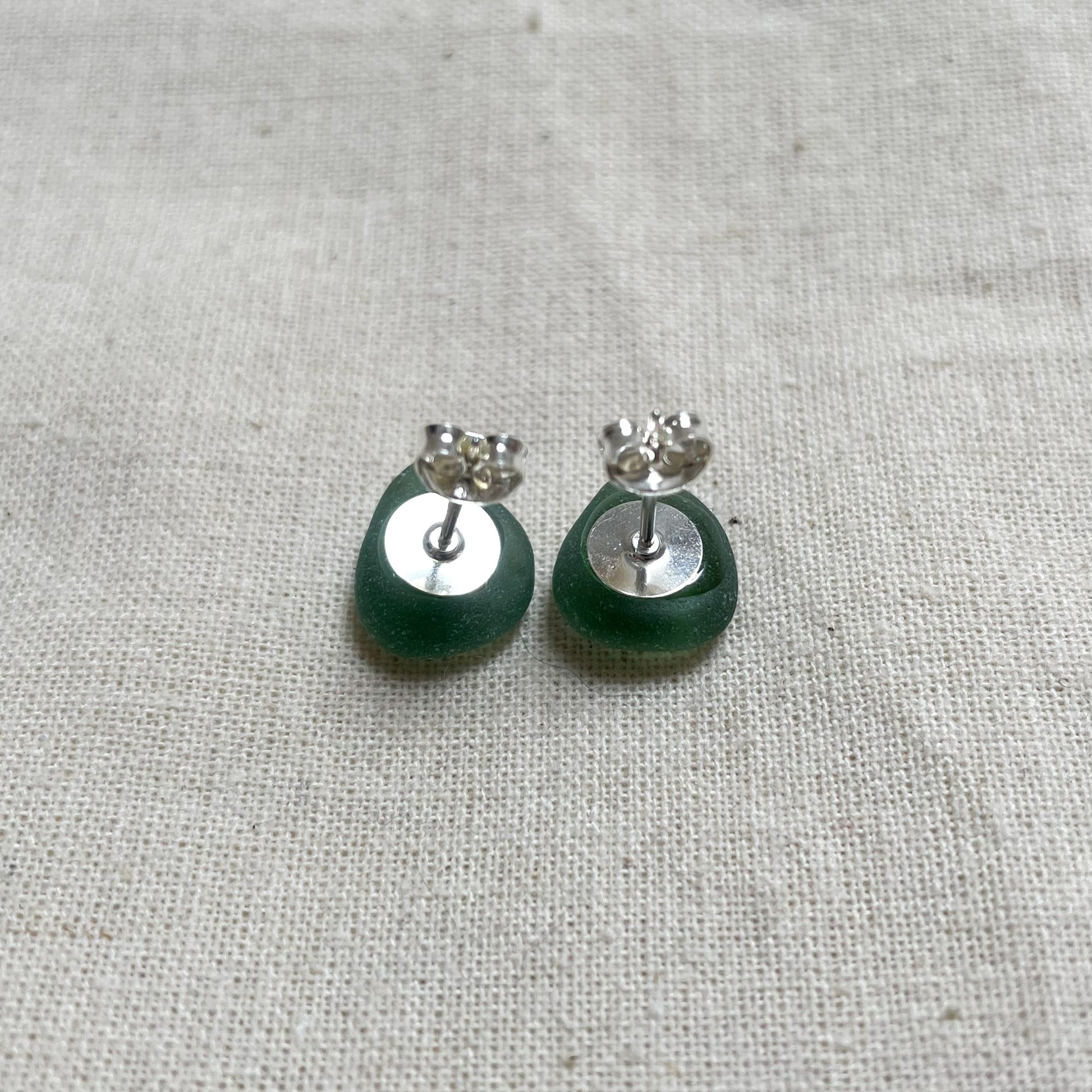 back of a pair of green sea glass stud earrings, showing the sterling silver ear post and butterfly back