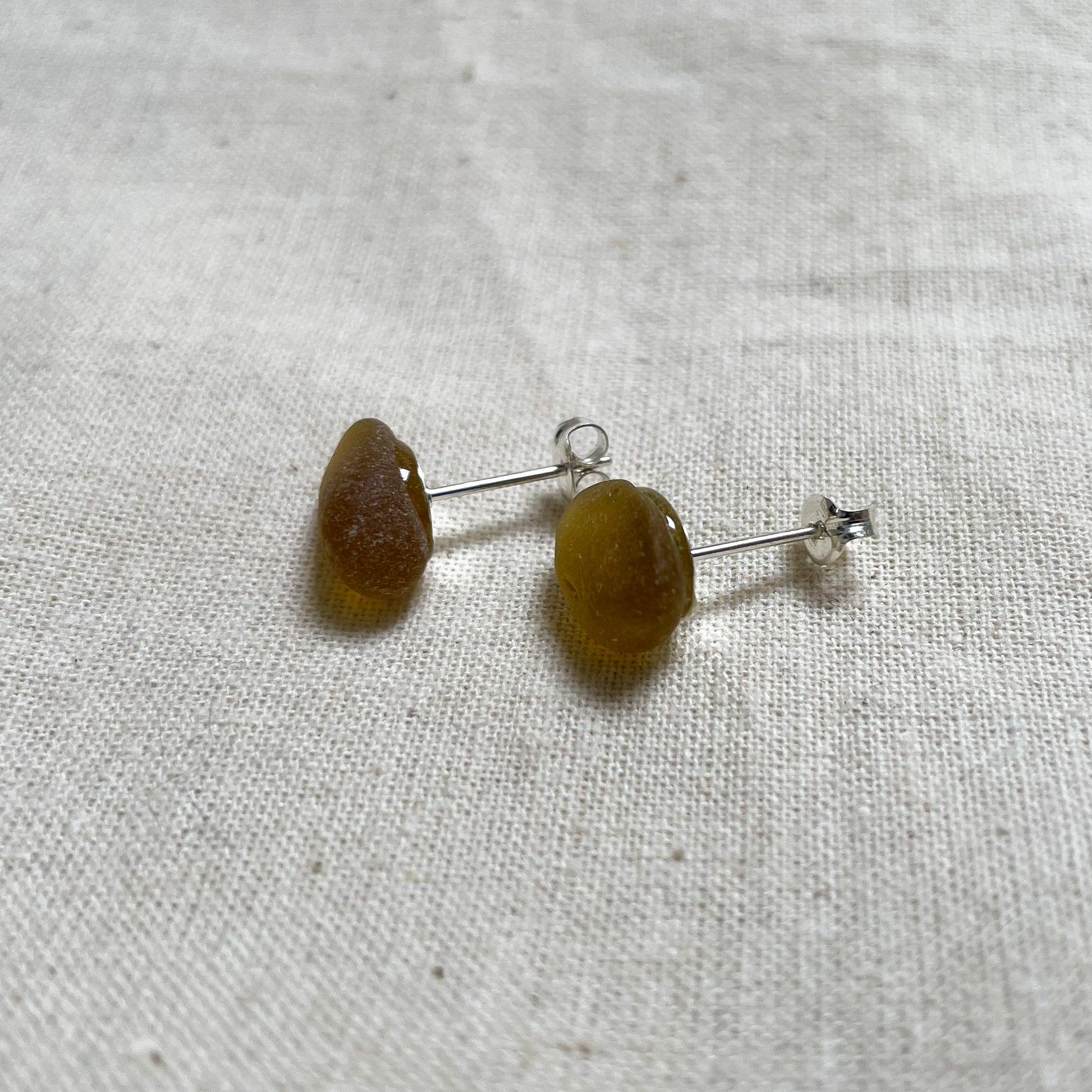 Side view of brown/yellow sea glass and sterling silver stud earrings