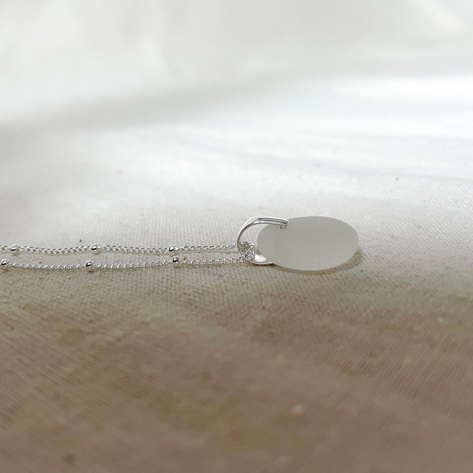 White sea glass pendant on silver satellite chain.