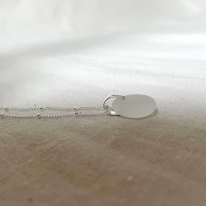 White sea glass pendant on silver satellite chain.