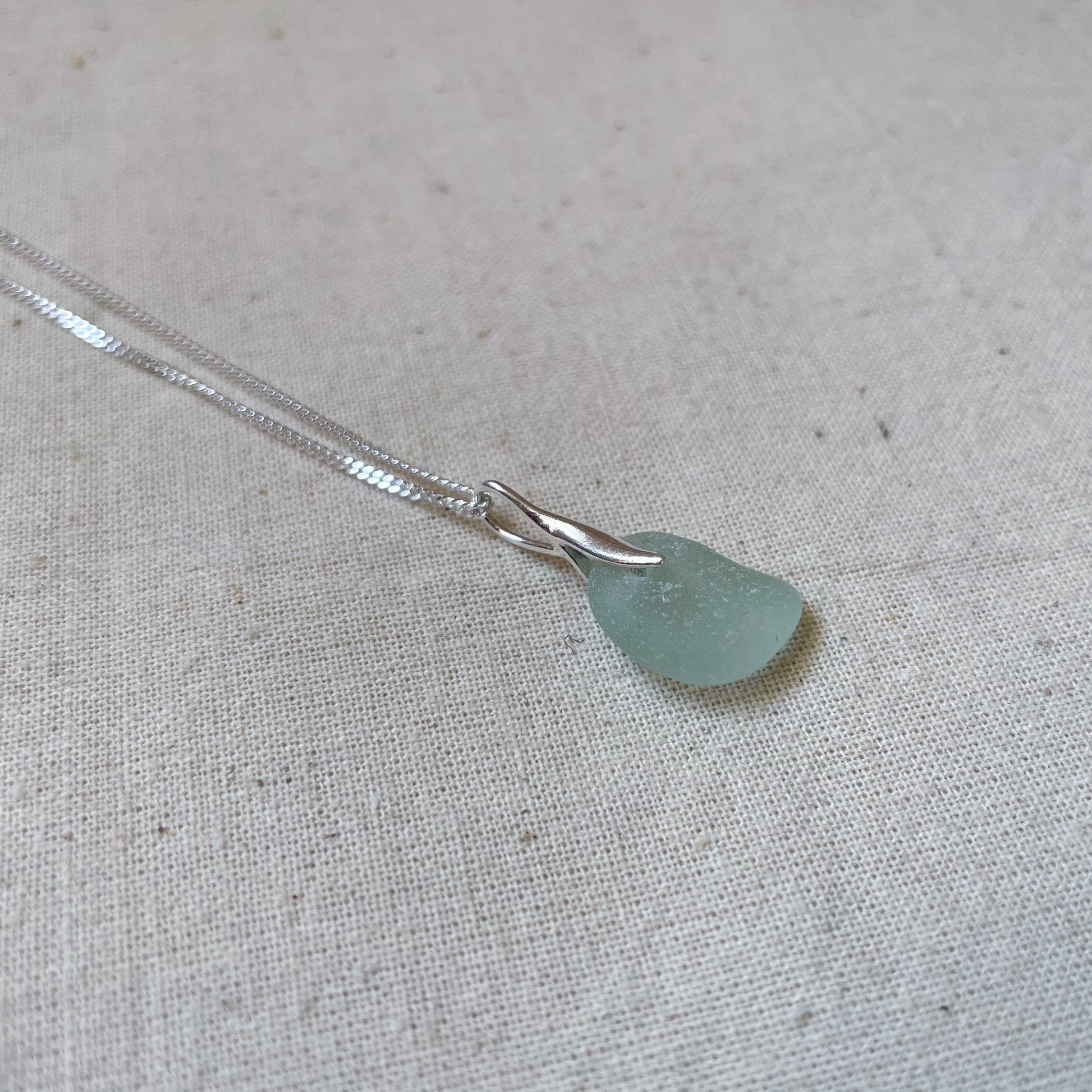 Light blue sea glass necklace on beige background