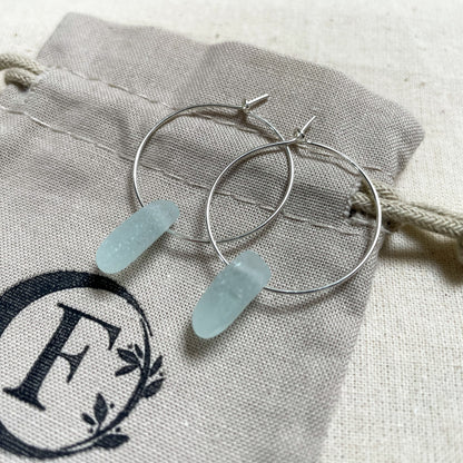 blue sea glass hoops laid on a beige cotton tie bag