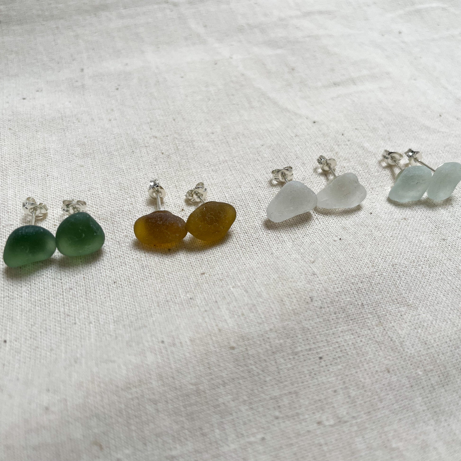 Four pairs of sea glass and sterling silver stud earrings in yellow (left), green (middle), white (middle) & light blue (right)