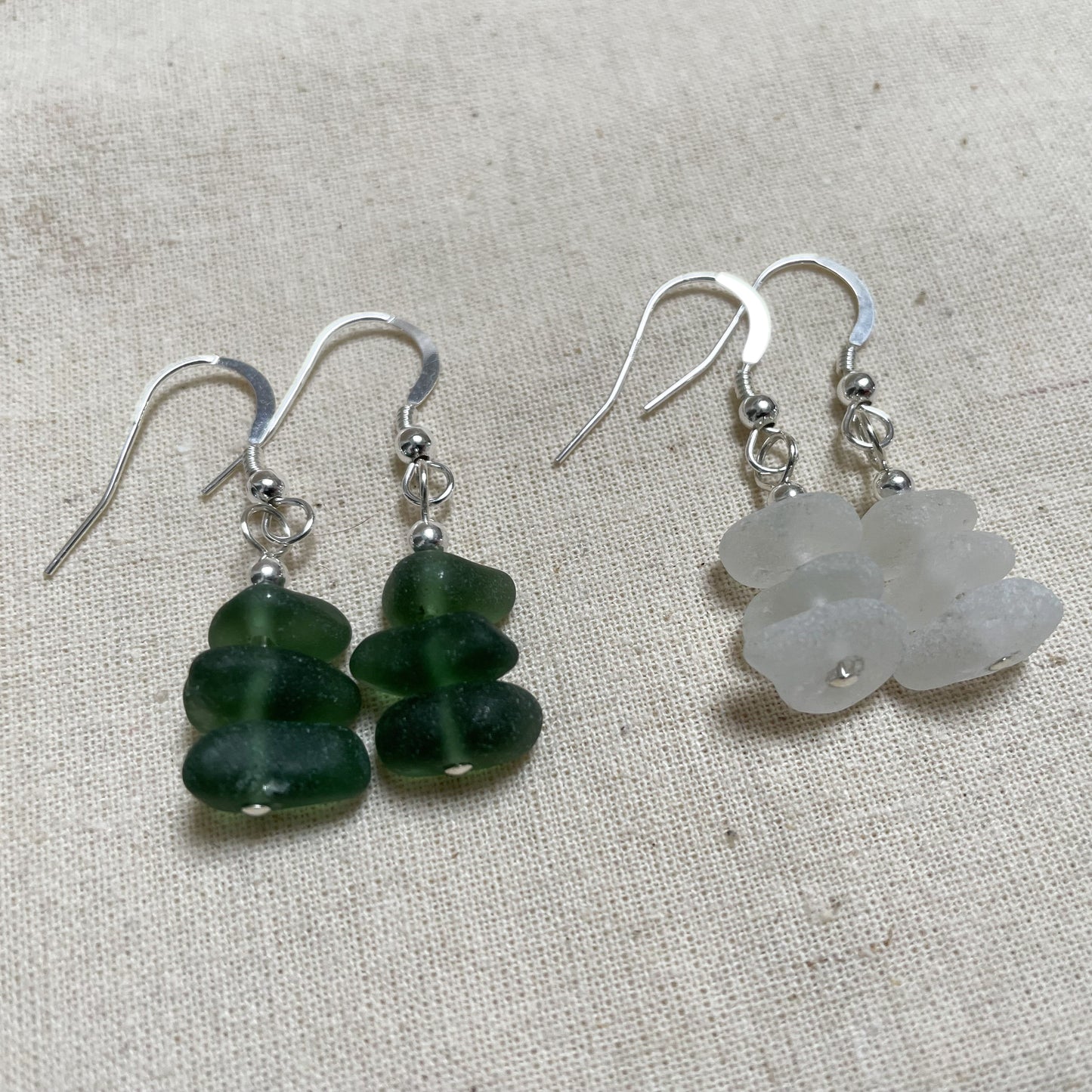 Green seaglass dangle earrings with silver ear wire (right), white sea glass dangle earrings (left)