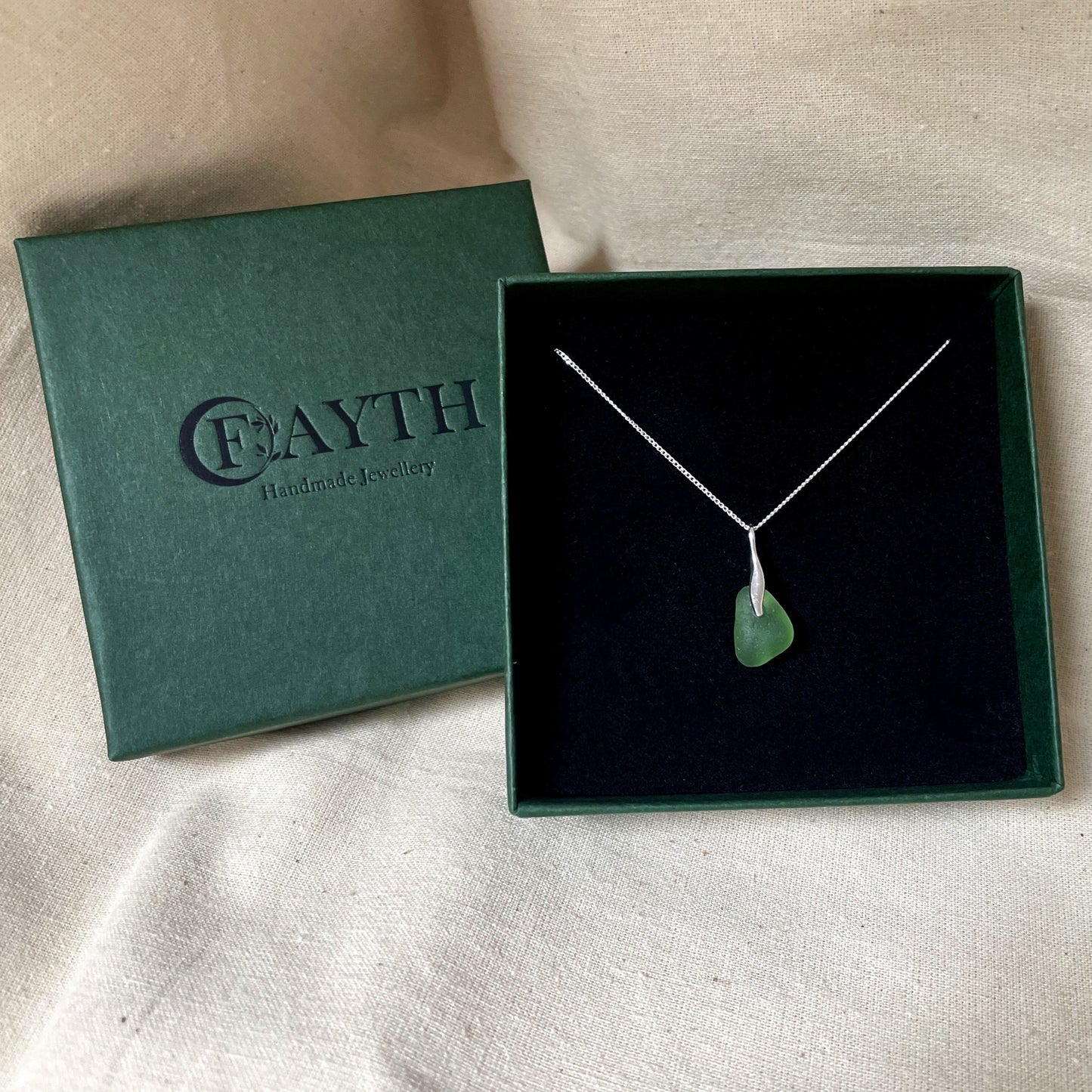 Green sea glass necklace on a fine silver chain in a dark green gift box with black foam insert