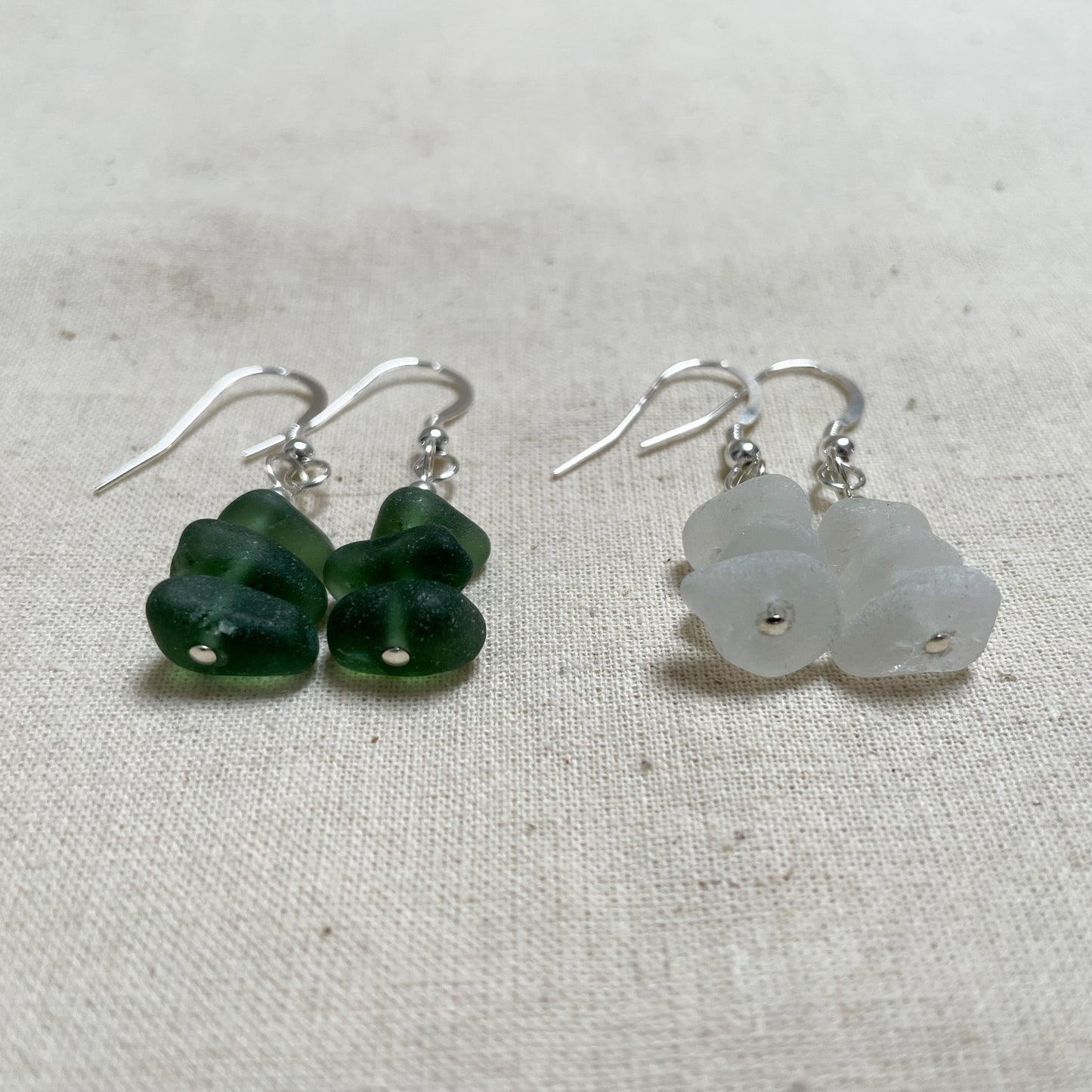 close up photo of the bottom of two pairs of earrings made from sea glass