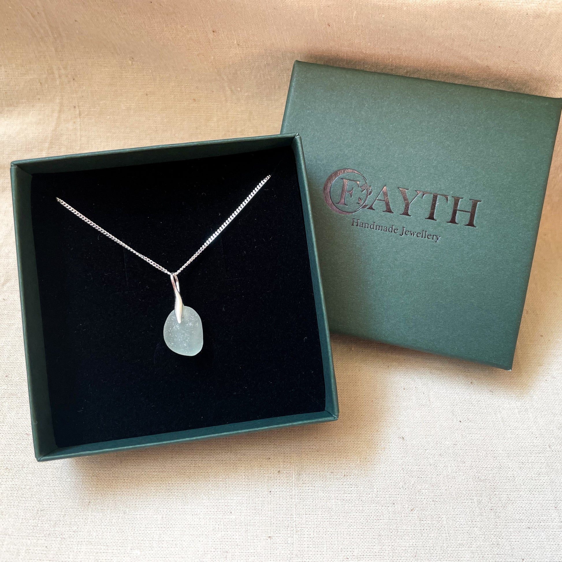 light blue sea glass necklace on a fine silver chain in a dark green gift box with black foam insert