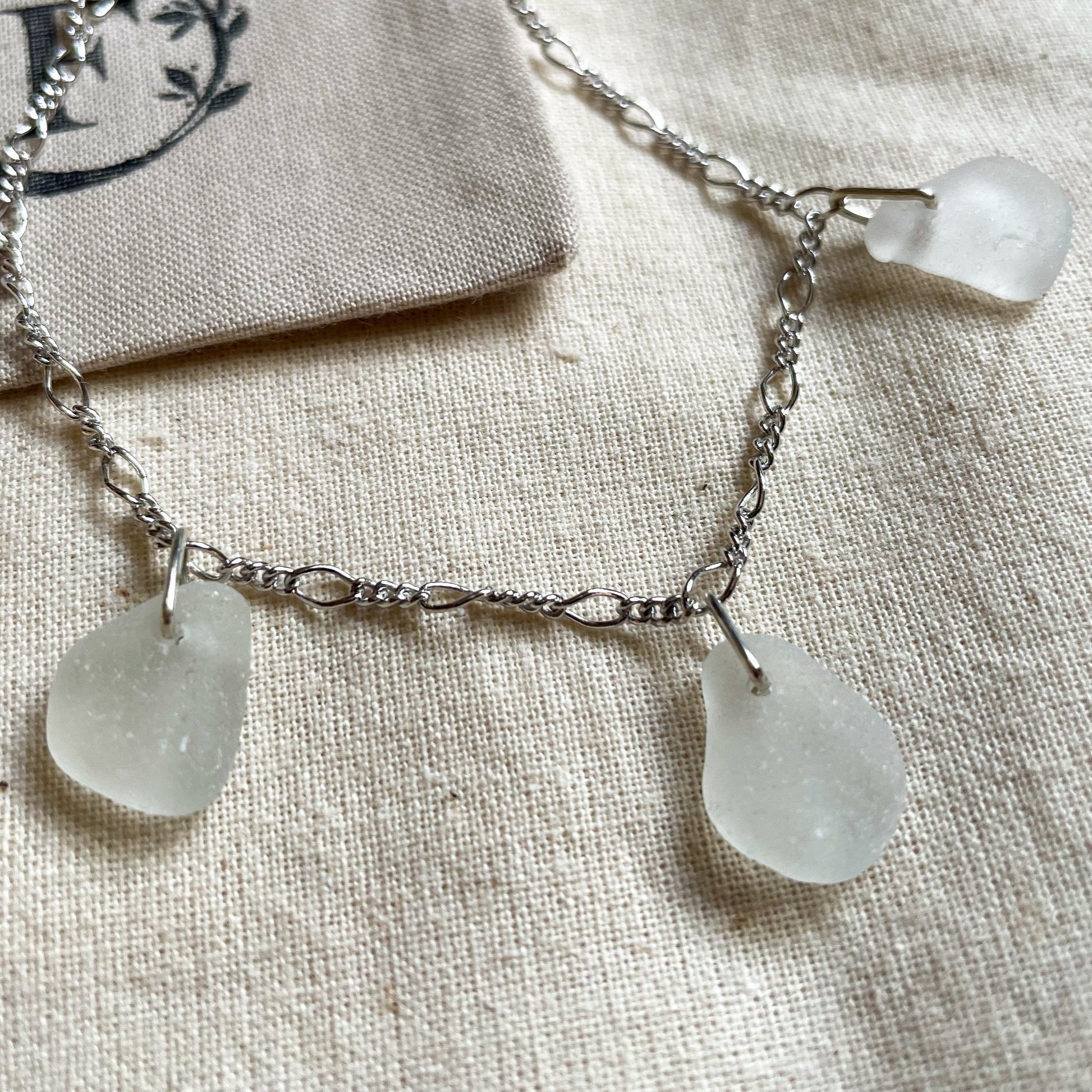 Sterling silver figaro chain bracelet with three pieces of white sea glass