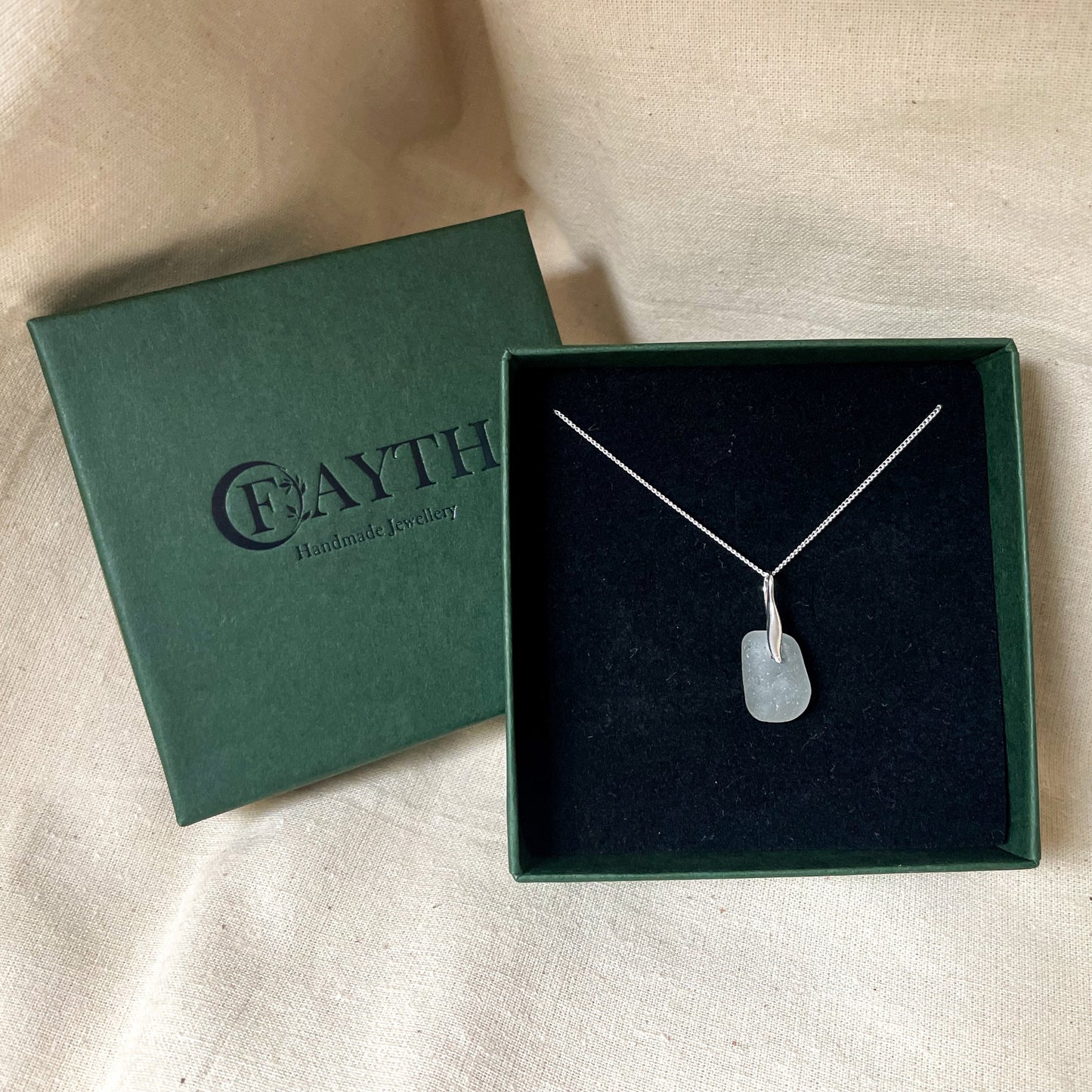 White sea glass necklace on a fine silver chain in a dark green gift box with black foam insert